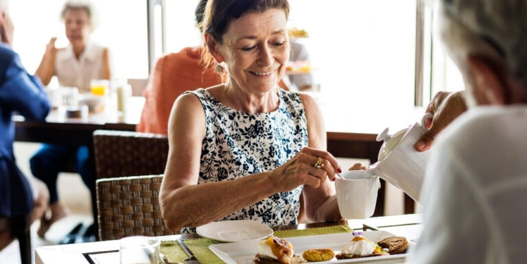 Woman Pouring Tea During Breakfast at Memory Care Facility